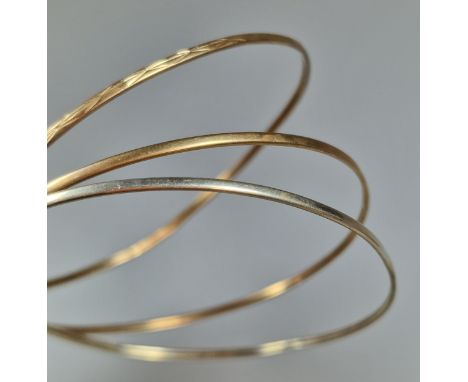 Two yellow metal bangles together with a white metal bangle (3). 5.6g approx. (B.P. 21% + VAT)