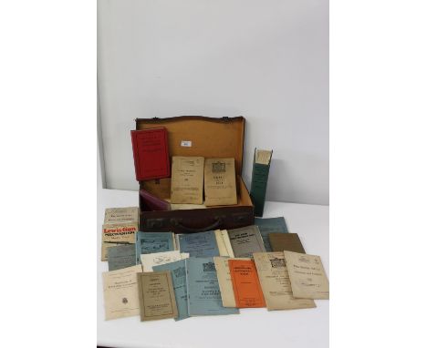 A vintage leather suitcase with military related manuals 