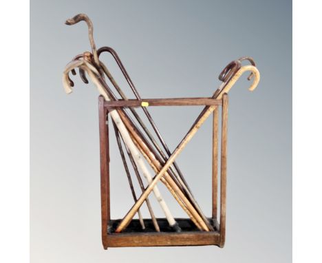 An Edwardian oak stick stand with lift out tray together with a quantity of assorted walking sticks, to include one with silv