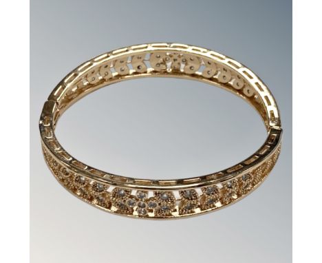 A yellow metal bangle with flower and leaf pattern, unmarked.