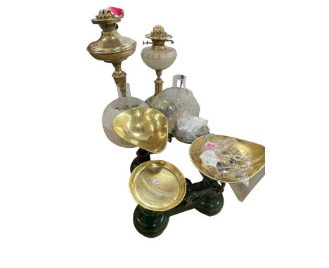 Two brass oil lamps with frosted and clear glass shades and two sets of kitchen scales and weights.