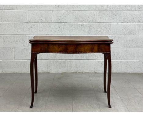 A Georgian mahogany card table having a fold over baize lined quatrefoil top over a carved serpentine frieze raised slender c