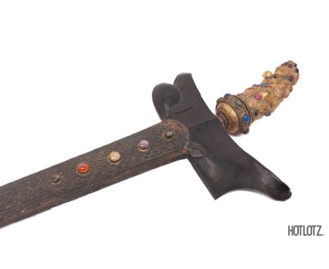 AN INDONESIAN KRIS WITH JEWELLED GILT-METAL HILT
With full wavy blade, the carved scabbard set with further semi-precious sto