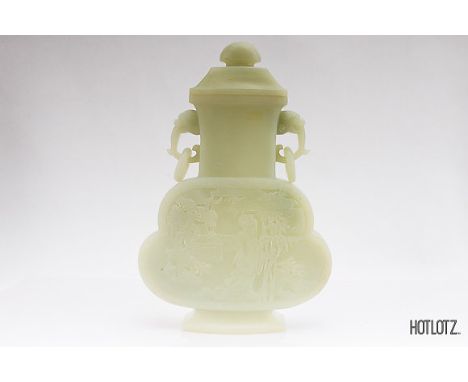 A CHINESE JADE TWIN HANDLED VASE AND COVER
Of shaped outline, the front carved in shallow relief with Guanine in a landscape 