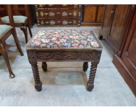 An oak bidet stool with tapestry seat, the frieze carved with vine fruits on barleytwist legs