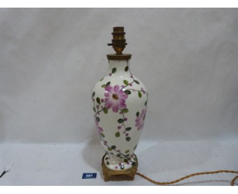A ceramic lamp base painted with flowers on ormolu base. 12½' high