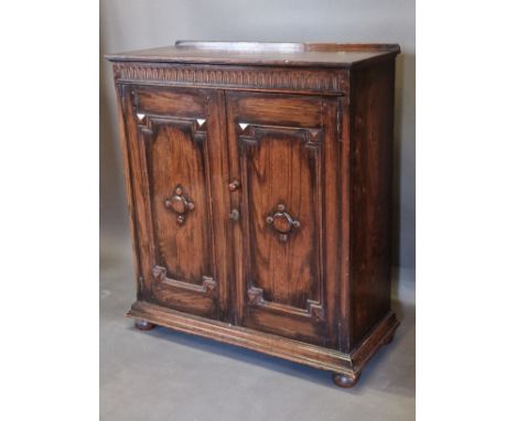 An oak side cabinet, the arcadian frieze above two panel doors raised upon low bun feet, 95cms wide, 40cms deep and 109cms ta