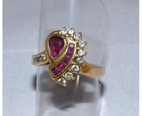 A modern yellow metal dress ring set with tear drop ruby, square cut rubies and 12 diamonds, in asymmetrical setting, stamped