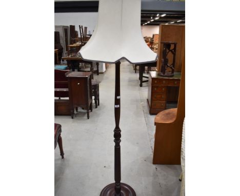 A turned and stained mahogany effect standard lamp with cream coloured shade