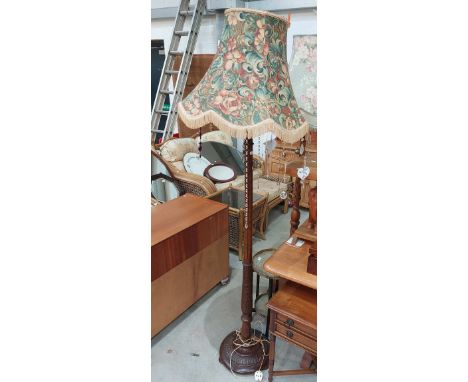 An early 20th century carved oak standard lamp, having acanthus type carving and floral Morris esque shade with a variety of 