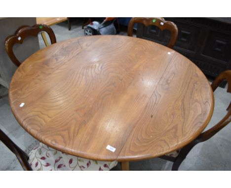 An Ercol circular dining table having drop leaves, on tapered splay legs