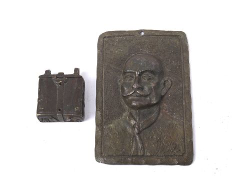 A novelty cast metal box and a metal plaque. The box modelled as a rucksack, L4.5cm, the plaque featuring a portrait of a gen