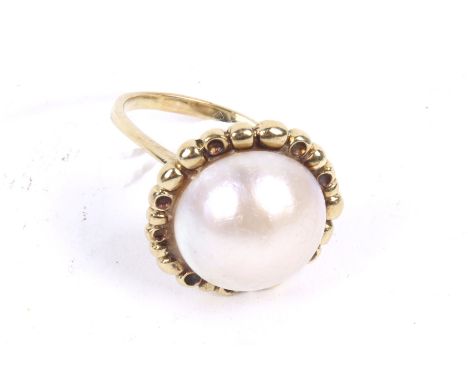 A vintage Continental gold and mabe pearl ring. The mabe pearl approx 15.5mm diameter, set within a beaded surround on a 'D' 