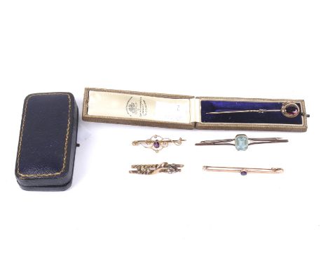 Four early 20th century gold and gem set bar brooches and an oval pyrope garnet stick pin. The stick pin with a garter surrou