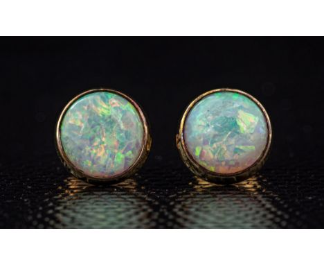 A pair of 9ct gold and opal stud earrings, the 7.5mm. cabochon opals of good colour and iridescence, within rub over settings