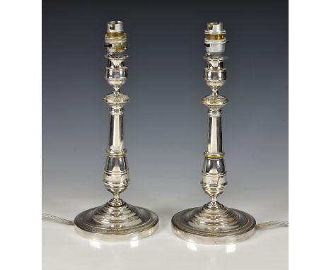 A pair of silver plated candlestick lamps, early 20th century, later converted to electricity, with urn nozzle, turned stem a