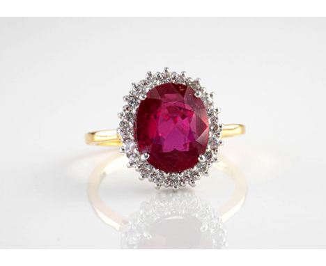 An 18ct yellow gold, ruby and diamond cluster ring, the central, oval cut ruby of deep crimson colour and weighing approximat