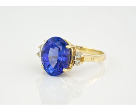 A 14ct yellow gold, tanzanite and diamond ring, the magnificent oval cut tanzanite measuring 11mm and held in a 4 pronged set