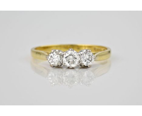 An 18ct yellow gold and diamond three stone ring, hallmarked London 1988, the centre 0.30ct brilliant cut diamond flanked by 