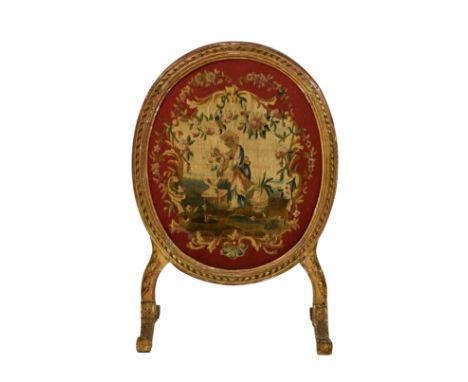 A George III oval giltwood firescreen, the curled ribbon decorated frame enclosing a tapestry panel depicting a lady in a gar