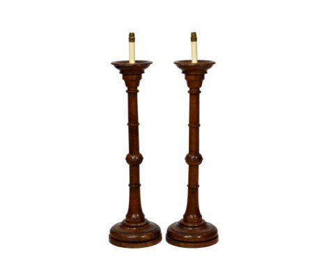 A pair of turned oak church candlestick lamps, mid-20th century, 36in. (91.5cm.) high plus fittings. (2) 