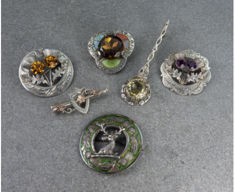 A collection of Scottish interest brooches, featuring two with thistle designs, studded with quartz; one featuring a deer's h