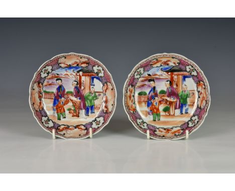 A pair of Chinese porcelain mandarin palette saucers, 18th century, deeply dished with barbed rim, enamelled with two noblewo