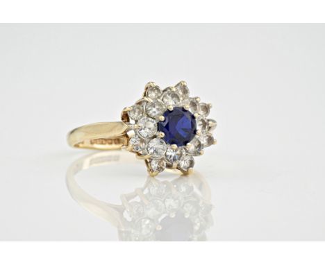 A 9ct yellow gold, sapphire and cubic zirconia cluster ring, the central, round cut sapphire surrounded by cubic zirconia in 