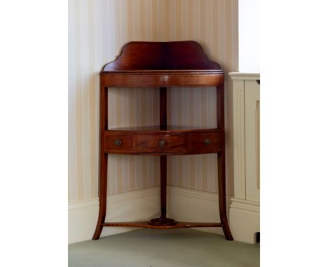 An early 19th century mahogany corner wash stand, the shaped back over a later fixed shelf, above a centre tier with centre d