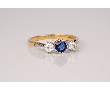 An 18ct white gold, diamond and sapphire trilogy ring, the central round cut sapphire of approximately 0.40ct and flanked by 