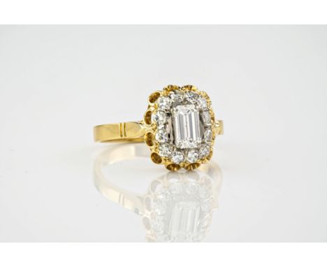 An 18ct yellow gold and diamond cluster ring, the central, emerald cut diamond measuring approx. 0.75ct and surrounded by rou