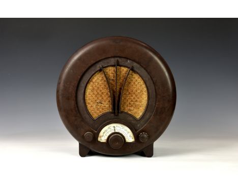 A vintage EKCO AD75 circular bakelite radio, brown bakelite, raised on bracket style feet, paper dial, marked, Ekco Type AD75