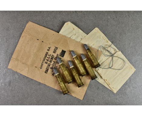 Six .577 Martini-Henry black powder centrefire rifle cartridges with spare packing, each cartridge stamped with letters K & I