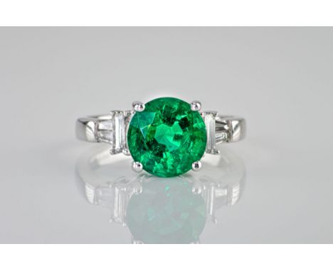 An impressive 18ct white gold, emerald and diamond ring, the central, round cut emerald weighing approximately 3.19ct and fla