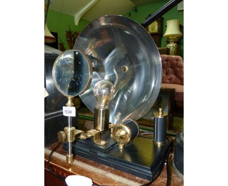 A scientific instrument Lamp with metal reflector dish and magnifying glass, 14" high x 9 1/2" wide.