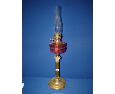 A Brass Corinthian column oil lamp with cut cranberry glass reservoir, with chimney, 30" tall including chimney.