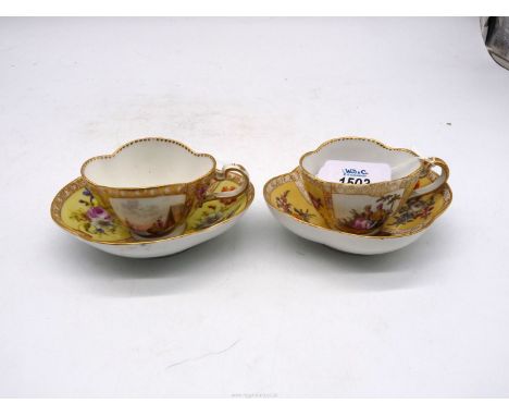 A pair of Meissen cabinet cups & saucers in quatrefoil shape; one with panels of courting couples, the other with panels of l