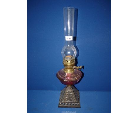 An Brass oil Lamp with cranberry glass reservoir and foliate detail metal base, 21 3/4" tall including chimney.