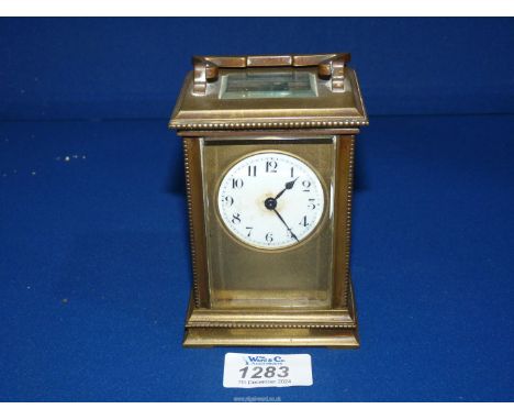 A French brass carriage clock having beveled glass panels, white dial within a gilt mask, shaped handle, with key, 3" wide x 
