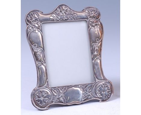 An Art Nouveau silver easel photograph frame, of shaped form, having embossed floral stylised decoration, housed on a velvet 