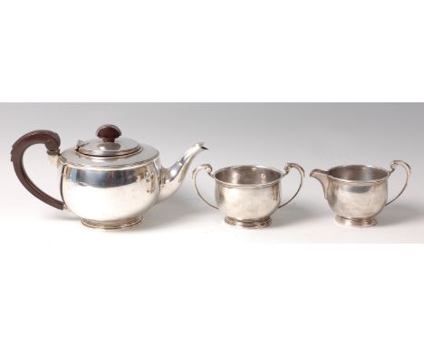 An Art Deco silver three-piece tea set, comprising teapot with hinged cover, twin handled sugar, and single handled cream jug