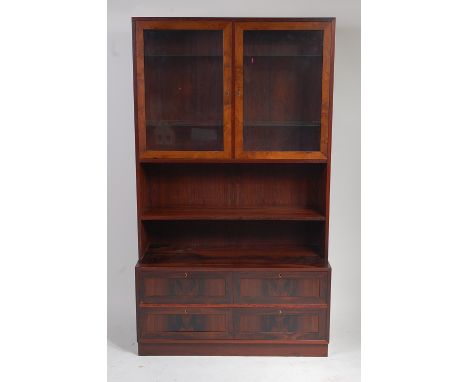 A 1960s Danish rosewood wall unit, possibly by Omann Jun, having twin glazed upper doors enclosing adjustable glass shelves, 