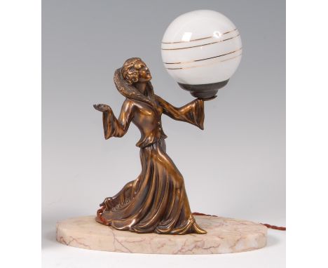 An Art Deco spelter table lamp, in the form of a standing woman holding milk glass globe shade, raised on red veined oval mar