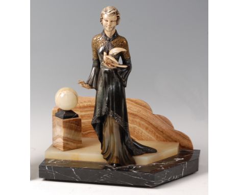 An Art Deco patinated spelter model of a robed standing woman holding a dove, raised on stepped and veined marble angular bas