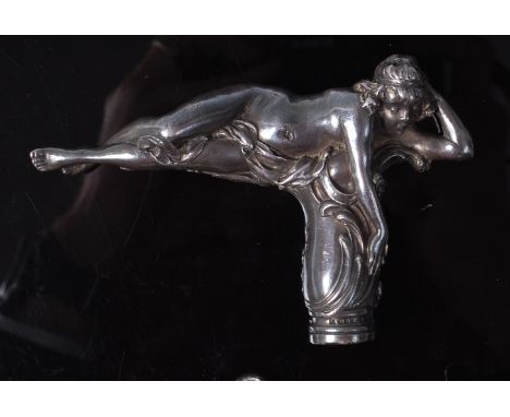 An Art Nouveau silver walking cane handle, in the form of a semi-nude female in recumbent pose, with further raised stylised 