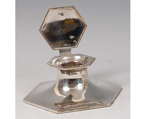 An early Art Deco silver hexagonal capstan inkwell, the hinged cover enclosing removable glass inkwell, the front edge with c