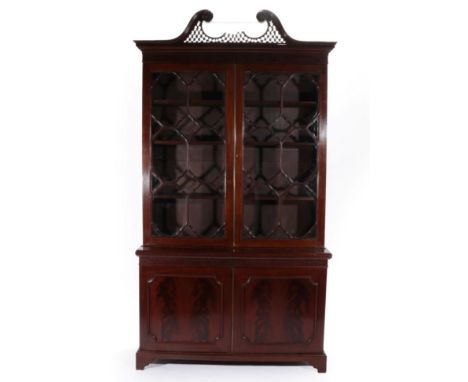 A Chippendale Revival Carved Mahogany Bookcase, 19th century, the blind fret carved swan neck pediment above a fret carved fr