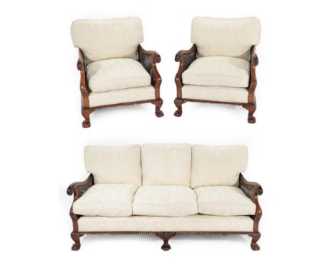 A Carved Mahogany Three Piece Bergère Suite, early 20th century, with double caned sides, comprising a three-seater sofa, wit