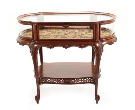 A Carved Mahogany Bijouterie Table, circa 1900, the moulded top with bowed end panels and pivoting door, on tapering legs wit