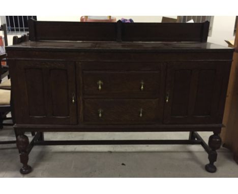 An oak sideboard/buffet with carved legs and central stretcher.